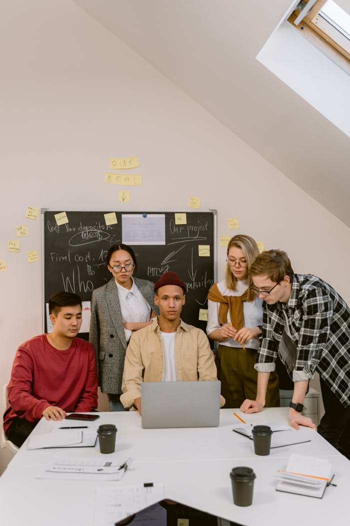 A diverse team brainstorming ideas in a modern office with laptops and sticky notes.